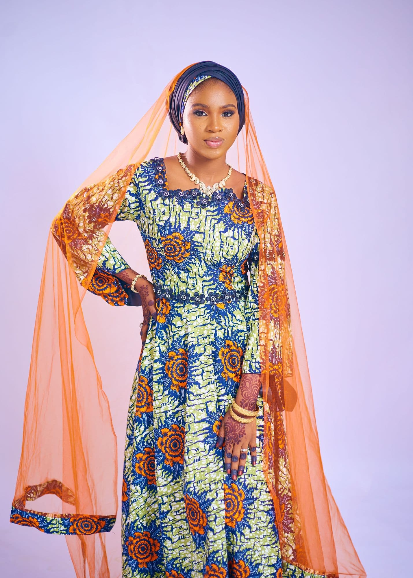 Model in a floral Ankara maxi dress with a sheer orange veil